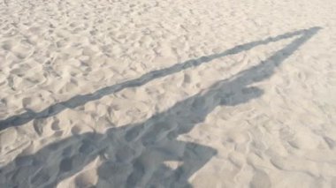 Çölde ya da kumsalda iple oynayan bir çocuğun gölgesi..