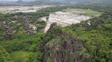 Pirinç tarlasının ortasındaki kaya dağı uçurumunun insansız hava aracı görüntüsü.