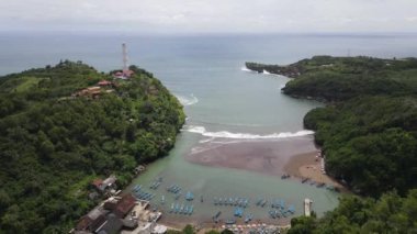 Endonezya Yogyakarta 'daki Baron plajının deniz feneri ve geleneksel tekneli görüntüsü.