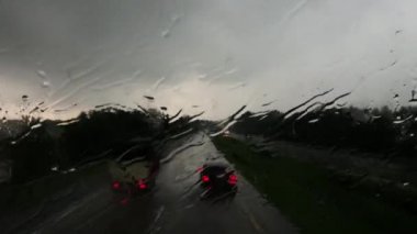 Blurry car front view driving on a highway in rain and hail in Indonesia.