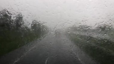 Blurry car front view driving on a highway in rain and hail in Indonesia.