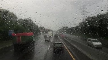 Blurry car front view driving on a highway in rain and hail in Indonesia.