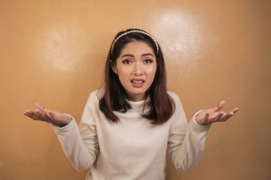 Beyaz gömlekli Asyalı güzel bir kızın kafa karıştırıcı jesti..