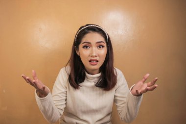 Beyaz gömlekli Asyalı güzel bir kızın kafa karıştırıcı jesti..