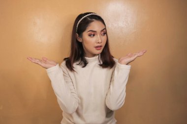 Beyaz gömlekli Asyalı güzel bir kızın kafa karıştırıcı jesti..