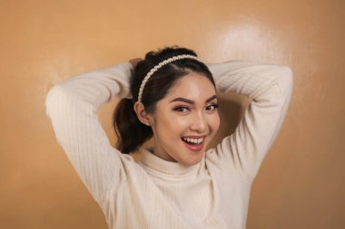 Saçlarını bağlayan gülümseyen genç Asyalı kadın. Saç bakımı. Güzellik konsepti.