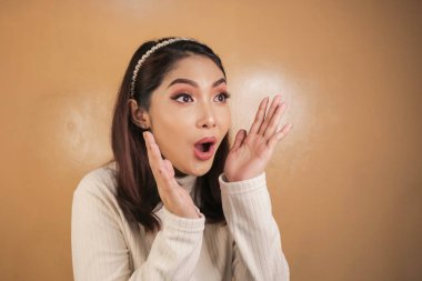 Eli açık Asyalı genç bir kadının şok olmuş yüzü. Reklam modeli konsepti.