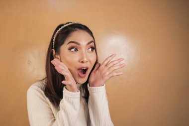 Eli açık Asyalı genç bir kadının şok olmuş yüzü. Reklam modeli konsepti.
