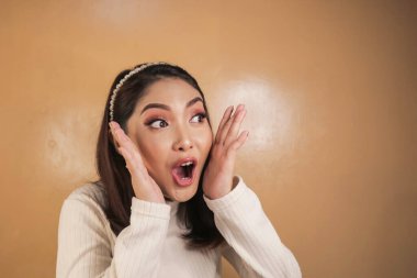 Eli açık Asyalı genç bir kadının şok olmuş yüzü. Reklam modeli konsepti.