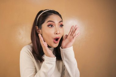 Eli açık Asyalı genç bir kadının şok olmuş yüzü. Reklam modeli konsepti.