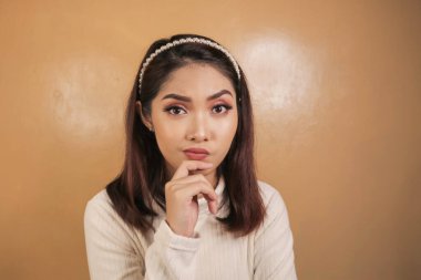 Elleri çenesinde genç ve düşünceli bir kadının portresi..