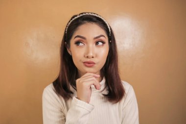 Elleri çenesinde genç ve düşünceli bir kadının portresi..