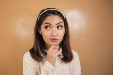 Elleri çenesinde genç ve düşünceli bir kadının portresi..