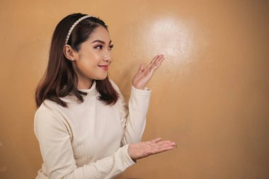 Mutlu ve gülümseyen yüz, boş alanda el işaretli genç Asyalı kızın gülüşü..