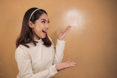 Mutlu ve gülümseyen yüz, boş alanda el işaretli genç Asyalı kızın gülüşü..