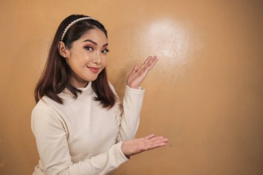 Mutlu ve gülümseyen yüz, boş alanda el işaretli genç Asyalı kızın gülüşü..