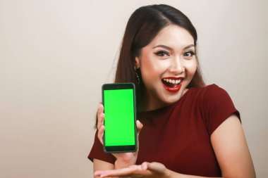 Mutlu ve gülümseyen Asyalı bir kadın yeşil boş bir ekrana işaret ediyor..
