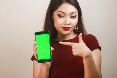 Mutlu ve gülümseyen Asyalı bir kadın yeşil boş bir ekrana işaret ediyor..