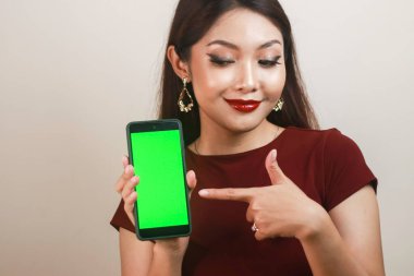 Mutlu ve gülümseyen Asyalı bir kadın yeşil boş bir ekrana işaret ediyor..