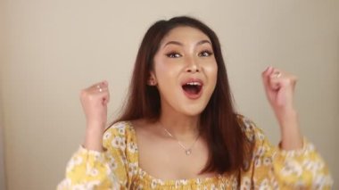 Sarı arka planda beyaz tişörtlü, uzun saçlı güzel bir kadın.