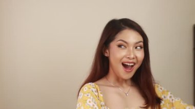 Sarı arka planda beyaz tişörtlü, uzun saçlı güzel bir kadın.