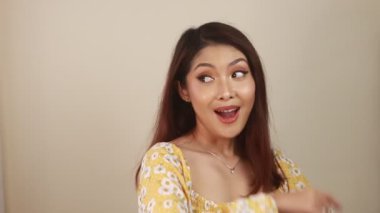 Mutlu ve gülümseyen yüz, boş alanda el işaretli genç Asyalı kızın gülüşü..