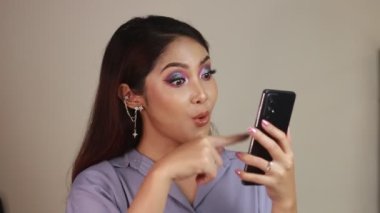 Mutlu ve gülümseyen Asyalı genç kadınlar yeşil boş bir ekran gösteriyorlar..