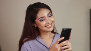 Mutlu ve gülümseyen Asyalı genç kadınlar yeşil boş bir ekran gösteriyorlar..