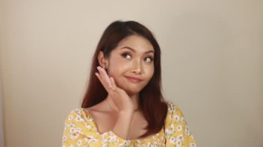 Beyaz arka planda uzun saçlı ve sarı elbiseli güzel bir genç kadın.