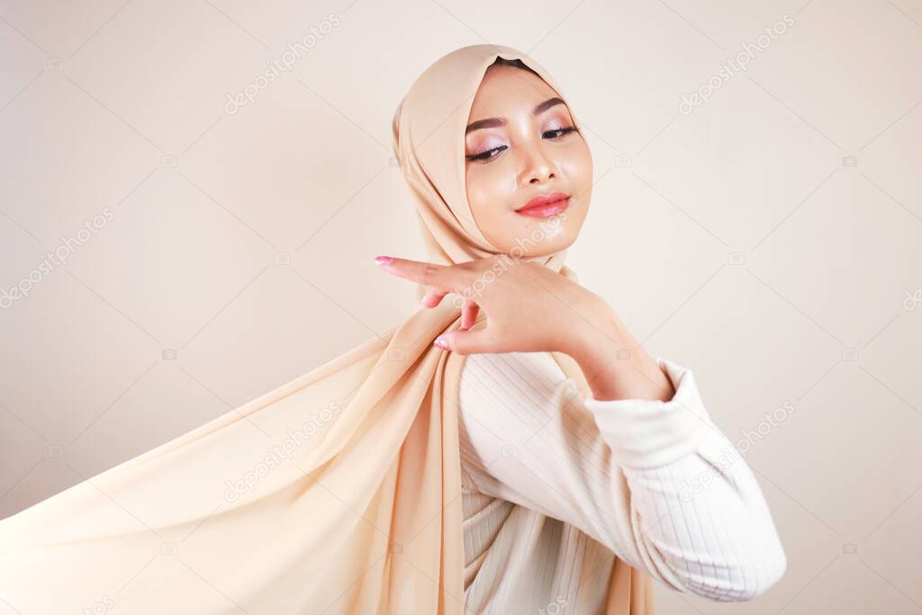 Muslim woman wearing traditional wear and hijab isolated on white background. Hijab is creatively made flying. Idul Fitri and hijab fashion concept.