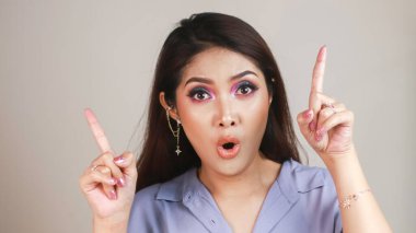 Güzel Asyalı genç bir kadının portresi beyaz arka planda izole edilmiş fotokopi alanını işaret ediyor ve şok ediyor.