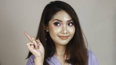 Beyaz arka planda renkli makyajlı güzel bir Asyalı kız çerçeveye bakar..