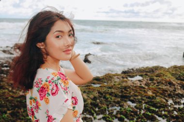 Sahilde genç bir Asyalı kız Gunungkidul, Endonezya 'da kameraya gülümsüyor.