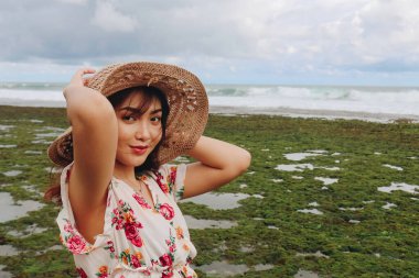 A young Asian girl wearing beach hat is relaxing on the blue sky beach at Gunungkidul, Indonesia