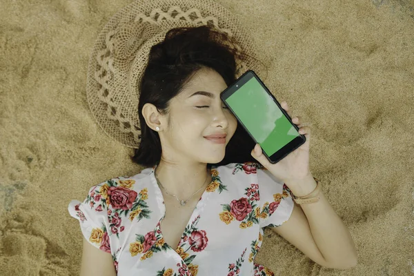 Young Beautiful Asian Woman Lying Sand While Showing Phone Screen — стокове фото