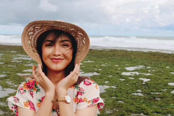 Plaj şapkası takan genç bir Asyalı kız Gunungkidul, Endonezya 'daki mavi gökyüzü kumsalında dinleniyor.