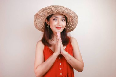 Hasır şapka takan genç ve güzel bir Asyalı kadın yüzünde kocaman bir gülümsemeyle selamlaşan eller veriyor. Beyaz arka planda Endonezyalı kadın.