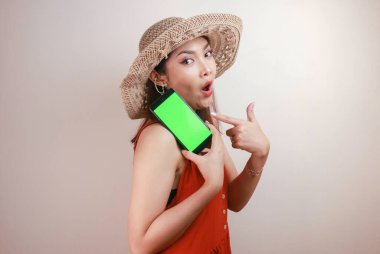 Heyecanlı ve şok olmuş Asyalı kadın elinde akıllı telefonuyla ekranı gösteriyor..