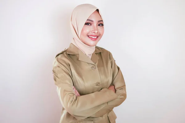 カメラには茶色の制服を着た若いアジア系ムスリム女性とヒジャーブの笑顔が描かれている インドネシア政府職員の制服 — ストック写真