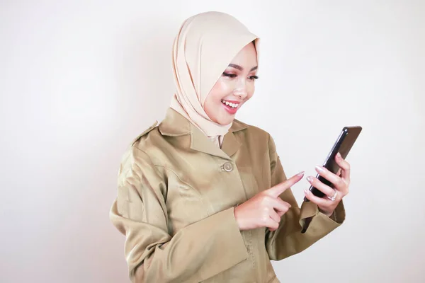 スマートフォンに空白の画面を表示する政府の労働者笑顔 カーキ色の制服とヒジャーブを着た若いアジア系ムスリムPns — ストック写真