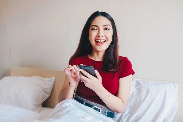 Uma Jovem Bela Mulher Asiática Sentada Cama Sorrindo Enquanto Segura — Fotografia de Stock