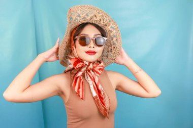 Genç Asyalı mutlu bir kadının mavi bir arka planda izole edilmiş seyahat konsepti..