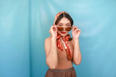 Genç Asyalı kadın kavramı, güneş gözlüğünü mavi bir arka planda tutuyor.