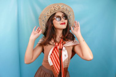 Genç Asyalı mutlu bir kadının mavi bir arka planda izole edilmiş seyahat konsepti..