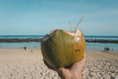 Tropik bir sahilde taze hindistan cevizi suyu resmi.