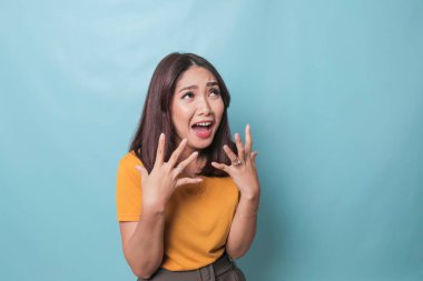 Beautiful young woman crying feeling very depressed isolated by blue background shouting loud