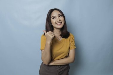 Young pretty woman smiling joyfully and looking happy, feeling carefree and positive with both thumbs up isolated by blue background