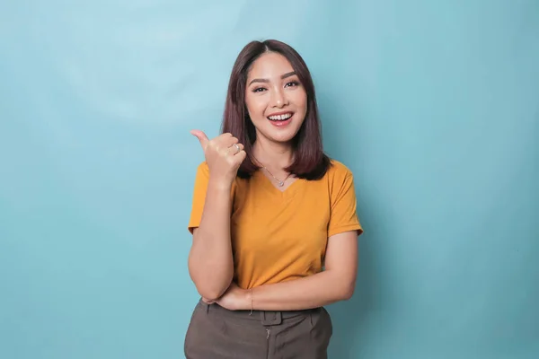 Young pretty woman smiling joyfully and looking happy, feeling carefree and positive with both thumbs up isolated by blue background