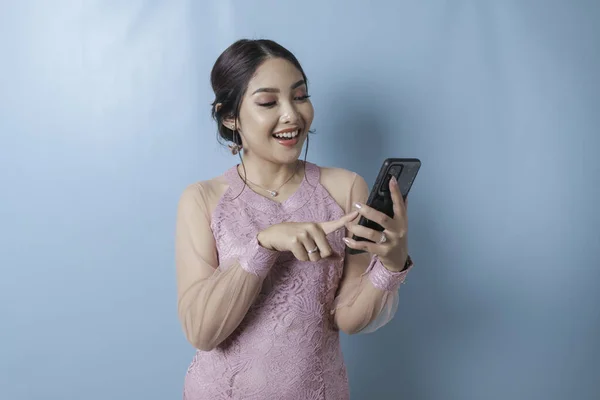 Excited Asian Woman Wearing Modern Kebaya Clothes Pointing Her Smartphone — Fotografia de Stock