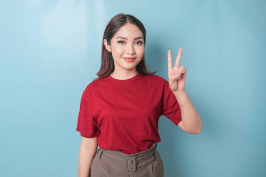 Excited Asian woman wearing a red t-shirt giving number 12345 by hand gesture